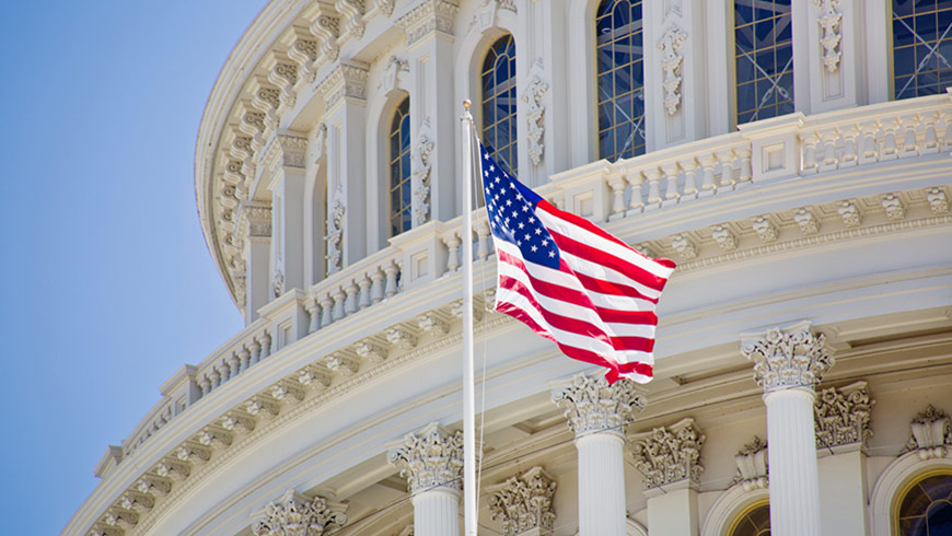 A United States national flag in front of the Capitol building in Washington DC