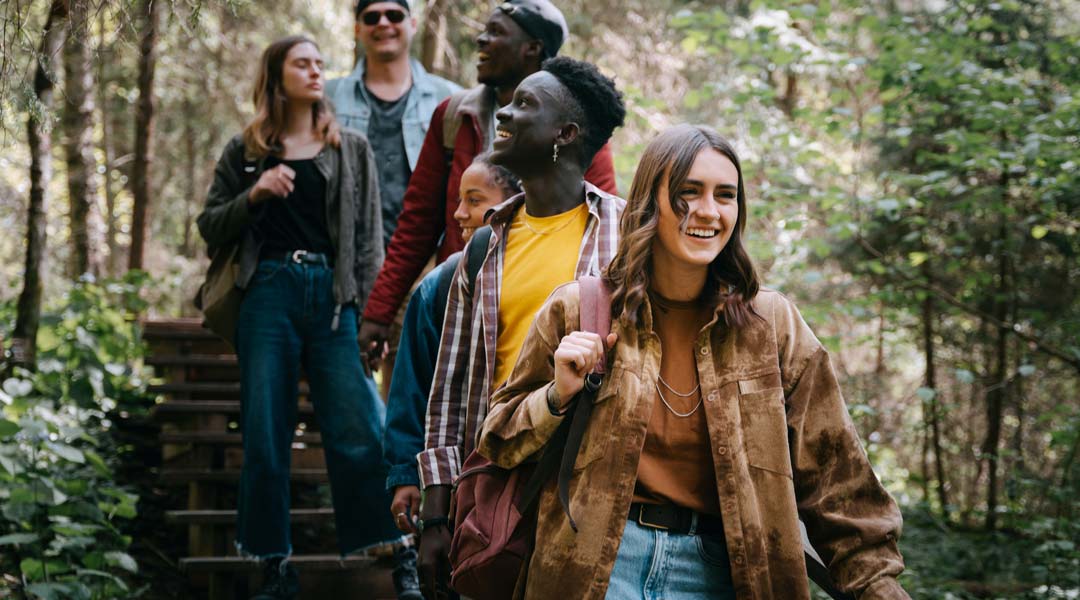Photo of a diverse group of young people walking through the woods